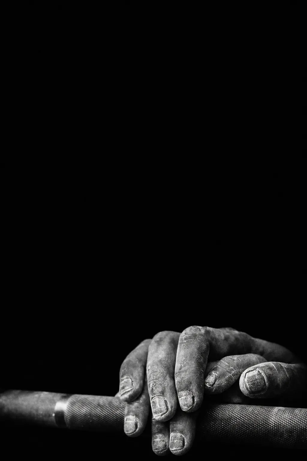Chalked hands resting on a barbell